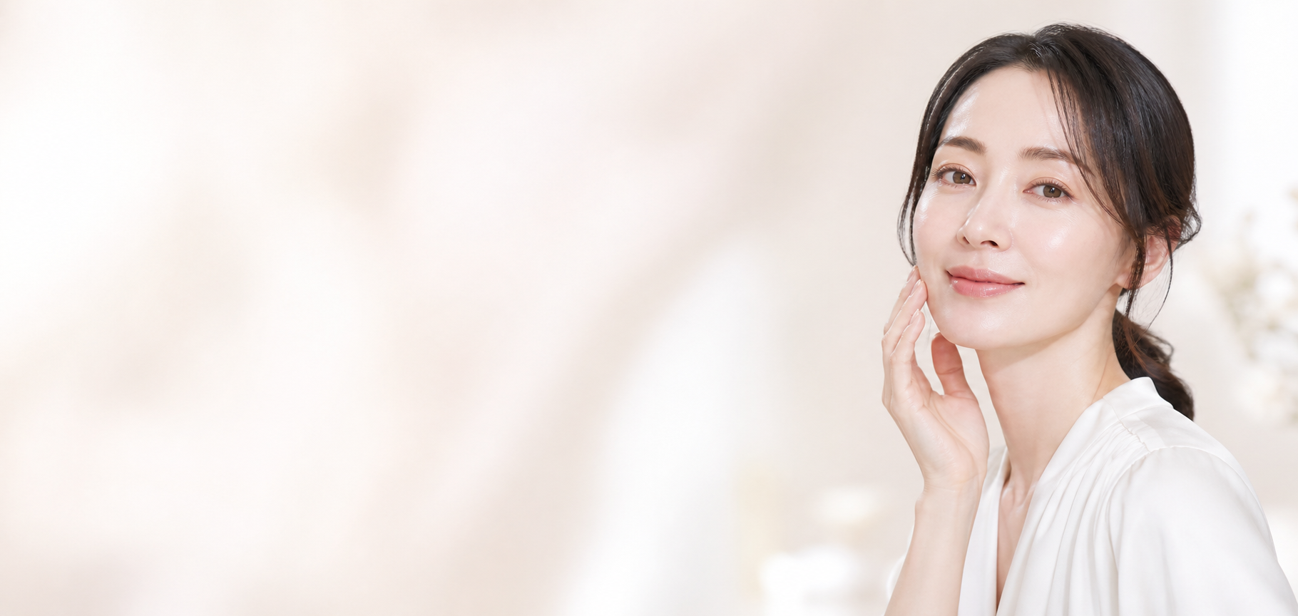 白い背景で頬に手を添える女性
